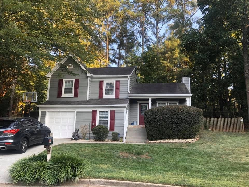 Two-story house exterior with gray siding and red shutters